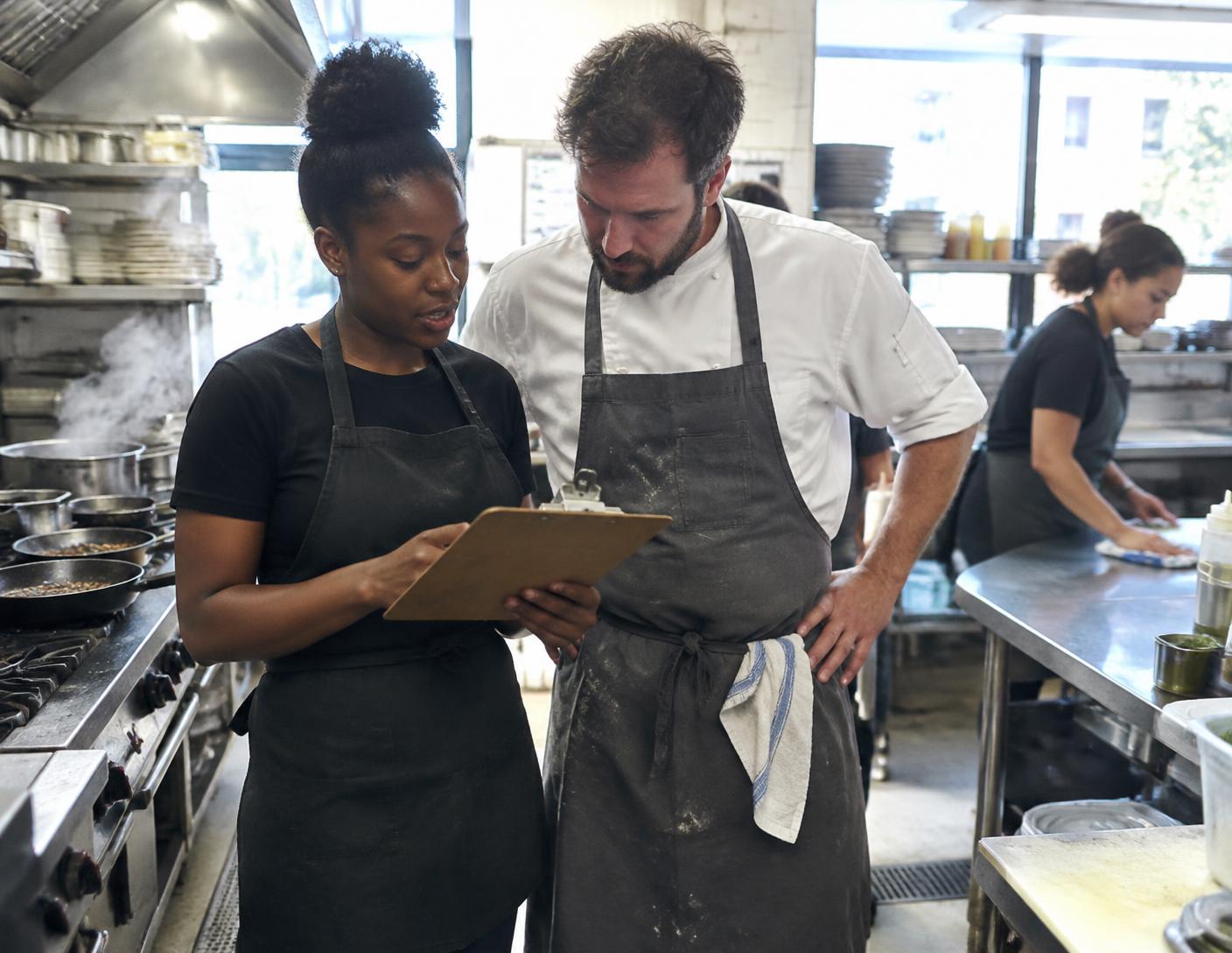 Consultant reviewing operations with a chef in a bright kitchen
